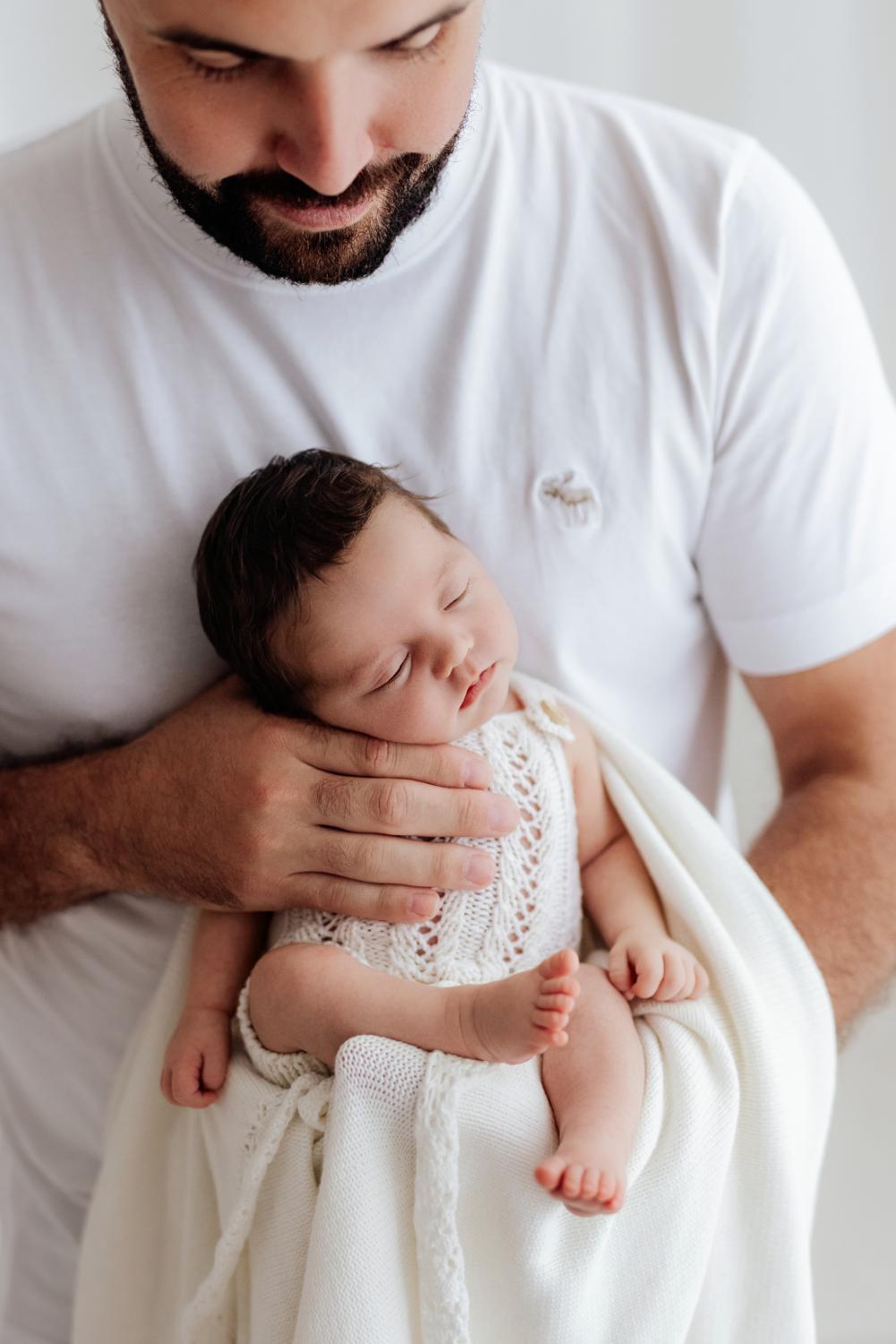  Otec drží novorodené bábätko počas štýlového newborn fotenia v ateliéri v Nitre 