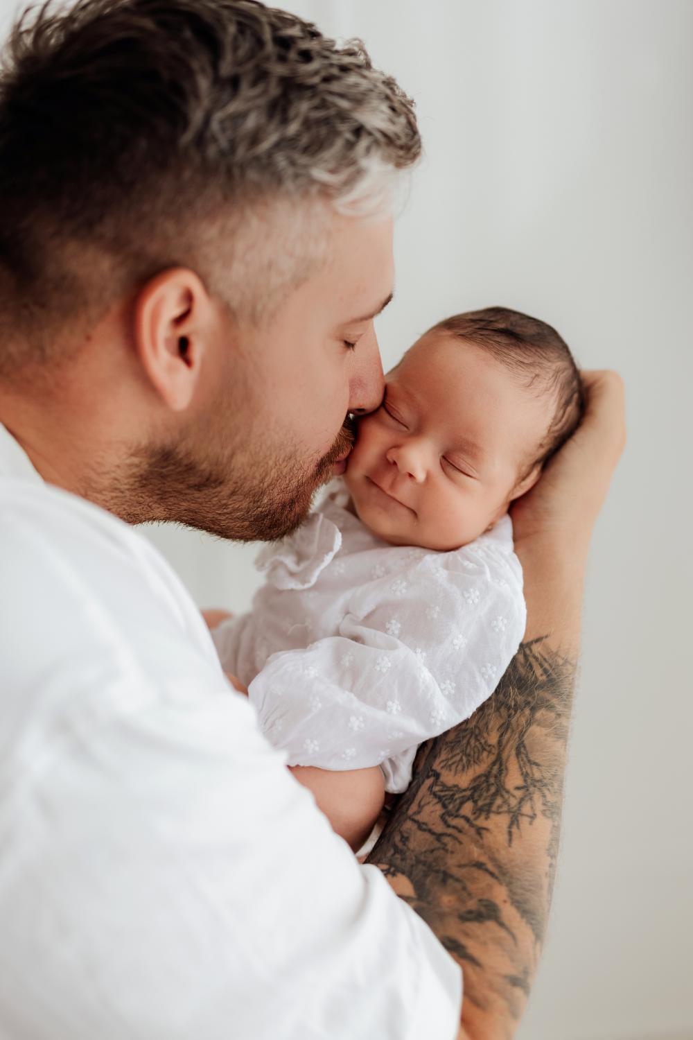  Otec nežne bozkáva bábätko na líce počas newborn fotenia v ateliéri v Nových Zámkoch 