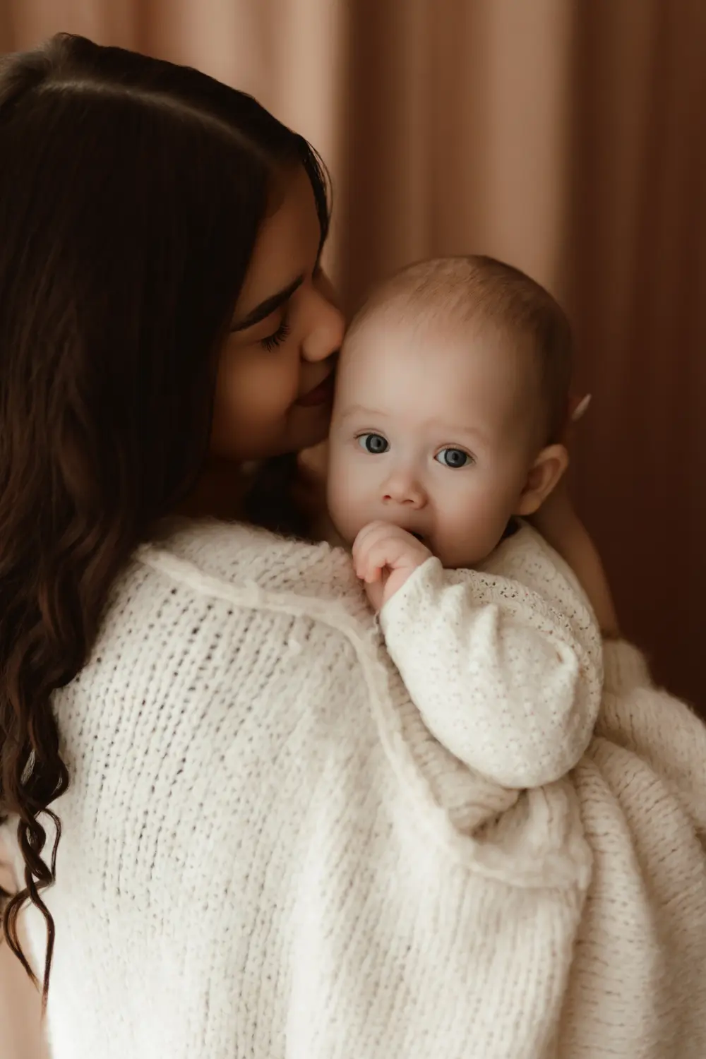 Mama bozkáva svoje bábúätko na hlavičku pričom ho drží v náručí počas prirodzeného materského fotenia v Nitre