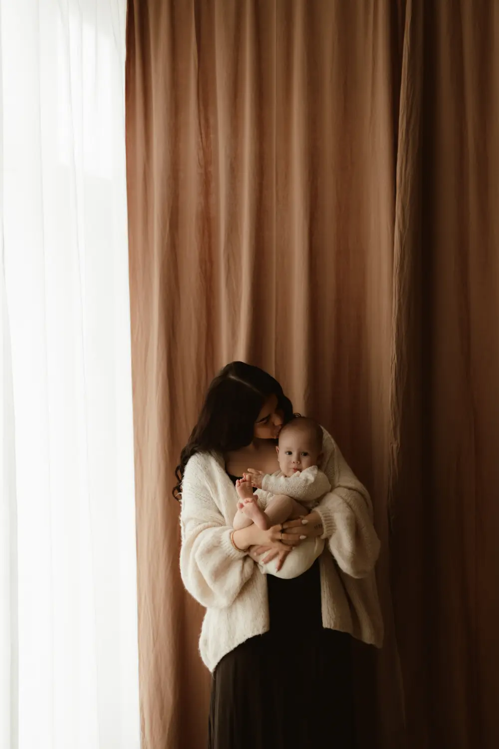 Mama bozkáva svoje usmiate bábätko počas pomalého fotenia mama a ja v ateliéri v Nitre