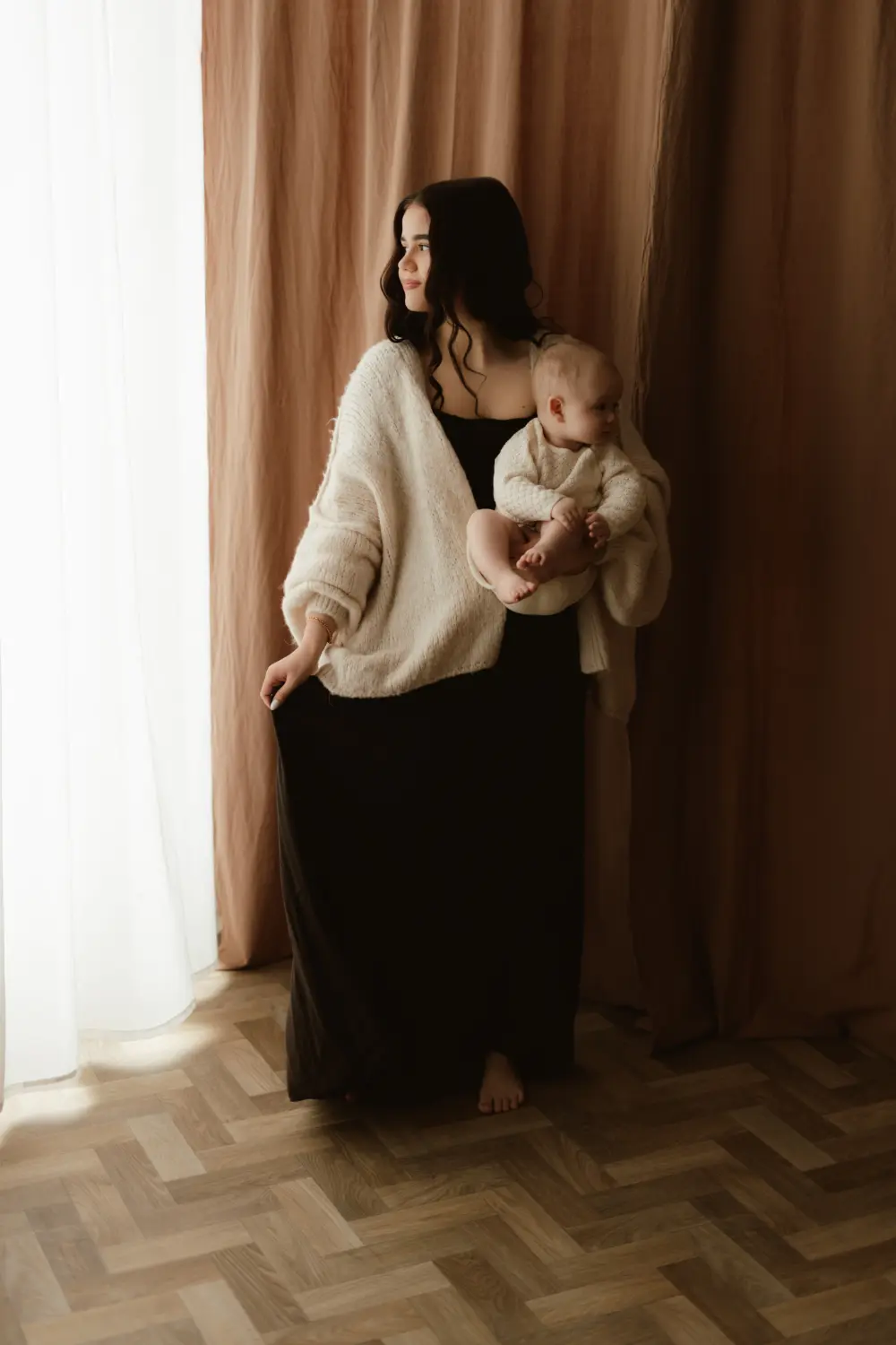 Nežný moment mama a dieťa zachtyený počas ateliérového rodinného fotenia v jemných zemitých farbách