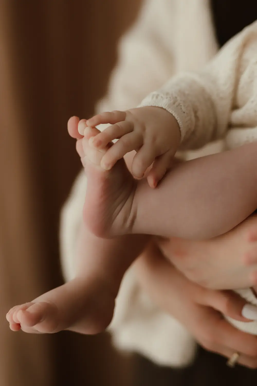 Detail ruky bábätka držiacej vlastnú nohu počas materského fotenia v ateliéri v Nitre