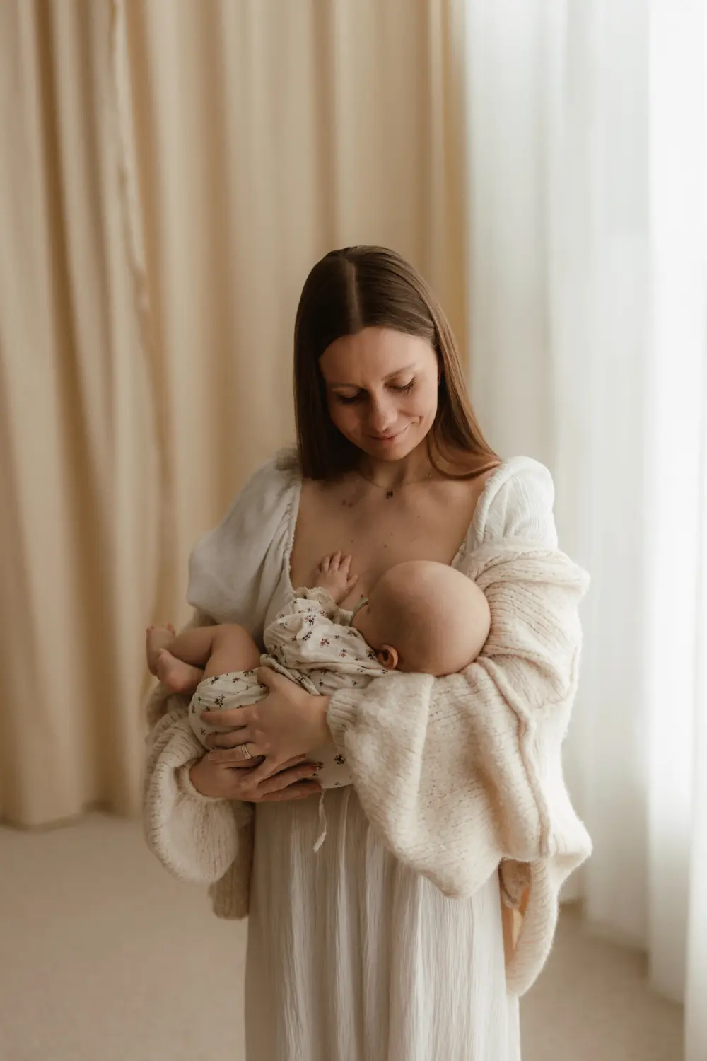  Matka sa šťastne pozerá na svoje bábätko počas uvoľneného materského fotenia v ateliéri v Novách Zámkoch 