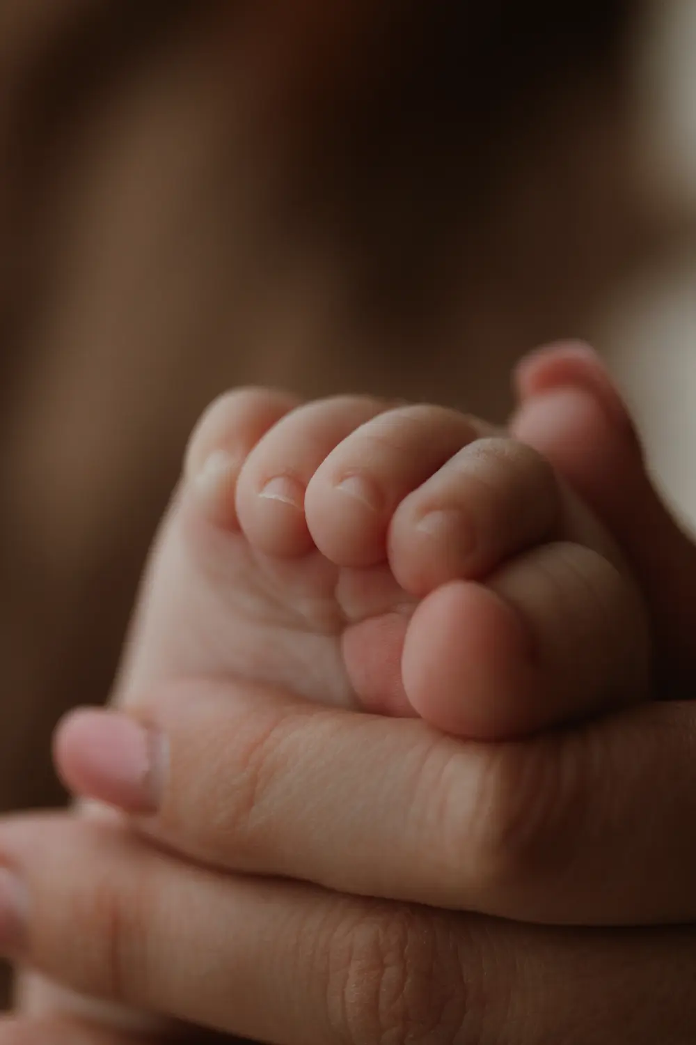  Detail nohy bábätka v dlani mami počas materského fotenia v ateliéri v Nitre a okolí 