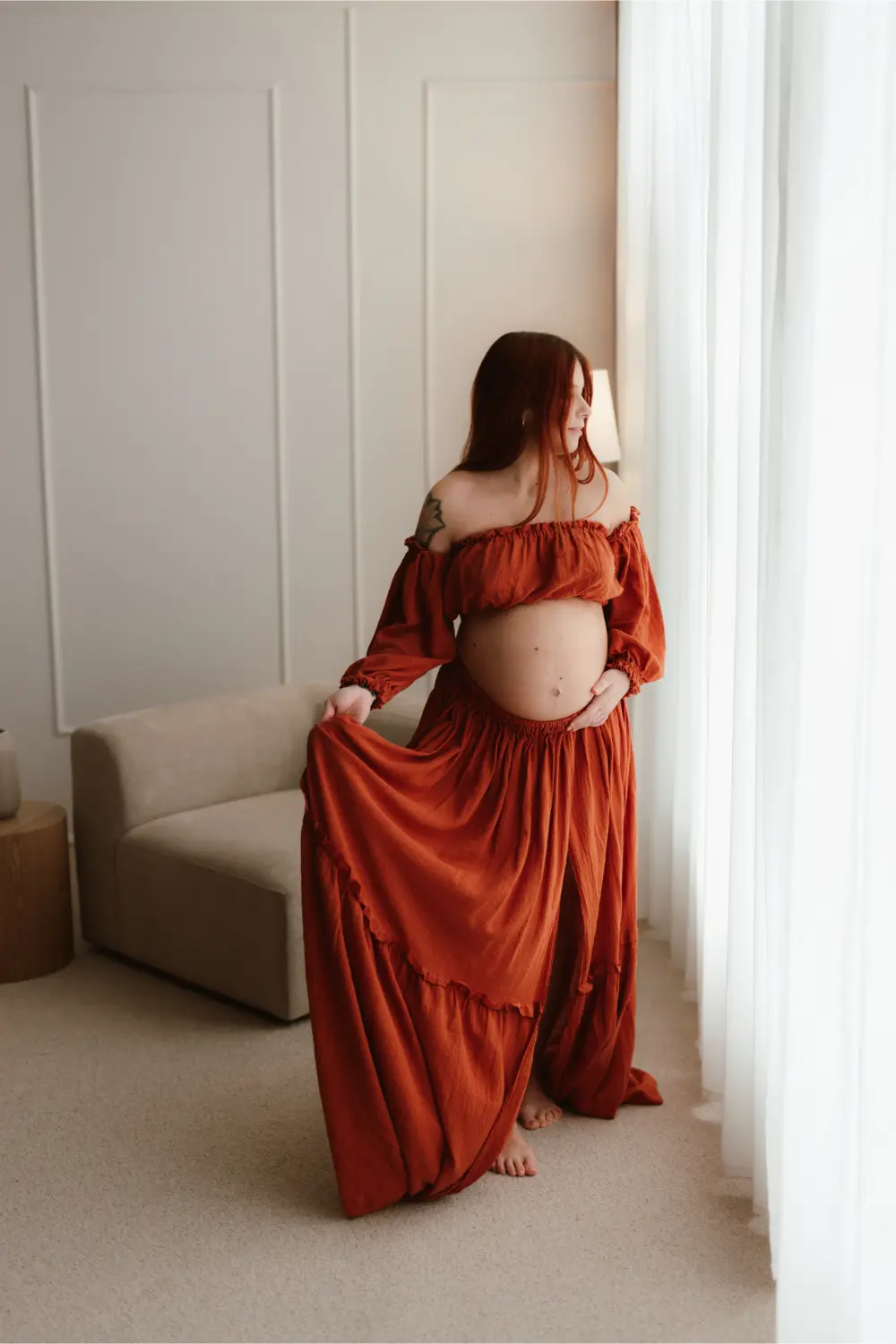  Tehotná žena pomaly hýbe pričom sa pozerá do okna počas tehotenského fotenia v ateliéri v Nitre 