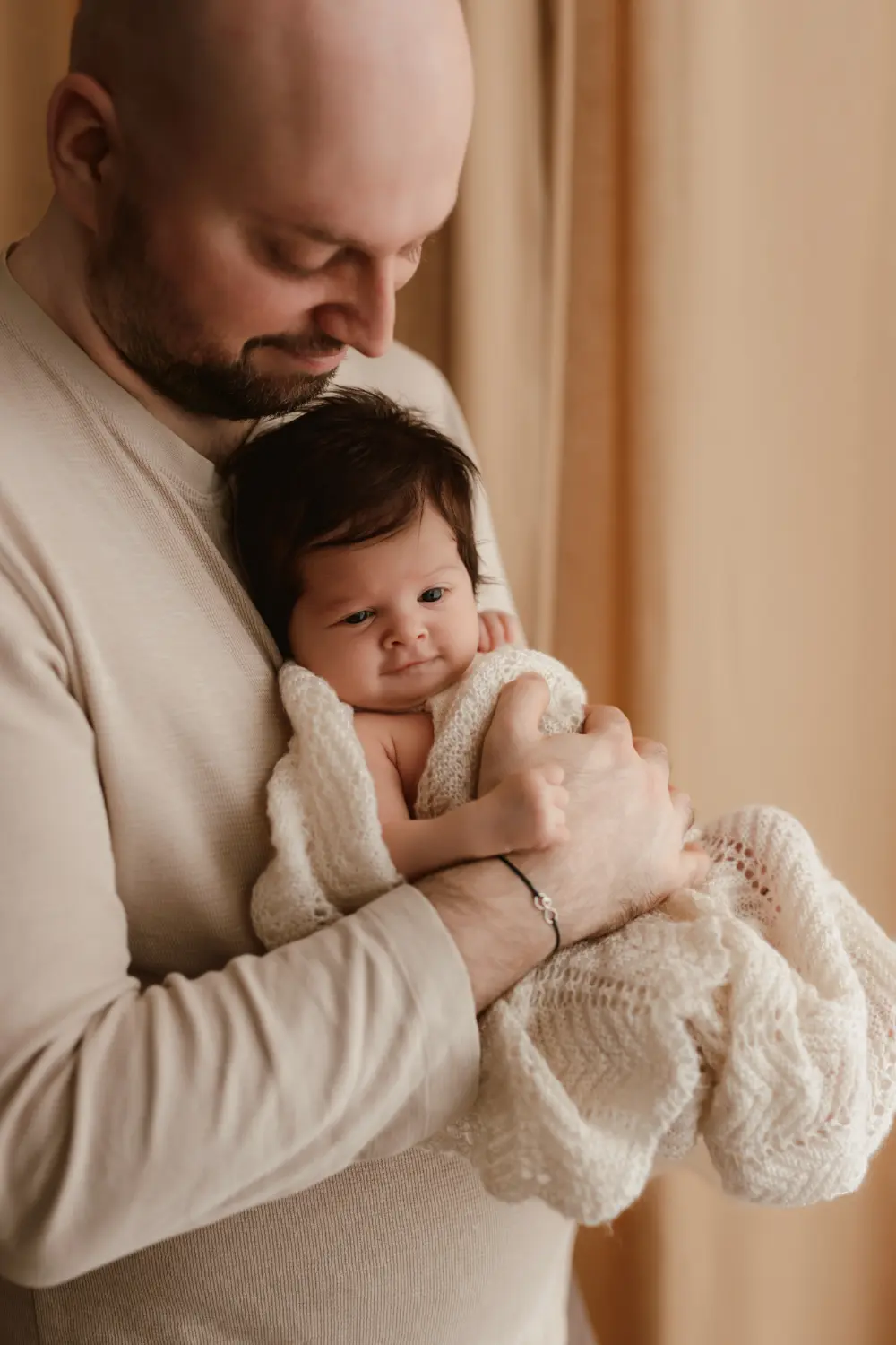 Bábätko sa zvedavo potzerá počas uvoľneného a štýlového newborn fotenia v ateliéri v Nových Zámkoch