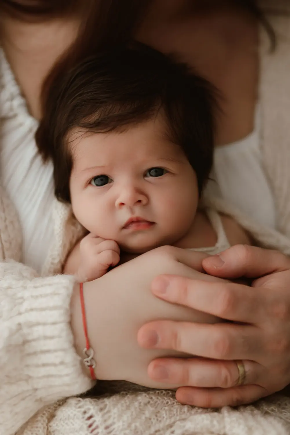 Bábätko sa zvedavo pozerá do objektívu počas prirodzeného newborn fotenia v ateliéri v Nitre