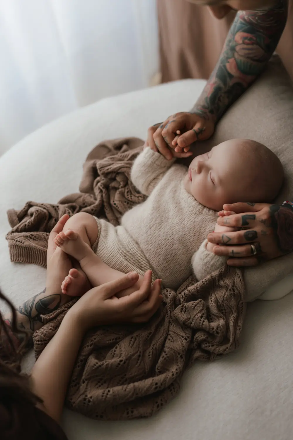 Rodičovské ruky prdržiavajúce spiace bábätko počas pokojného a bezpečného newborn fotenia v Nitre