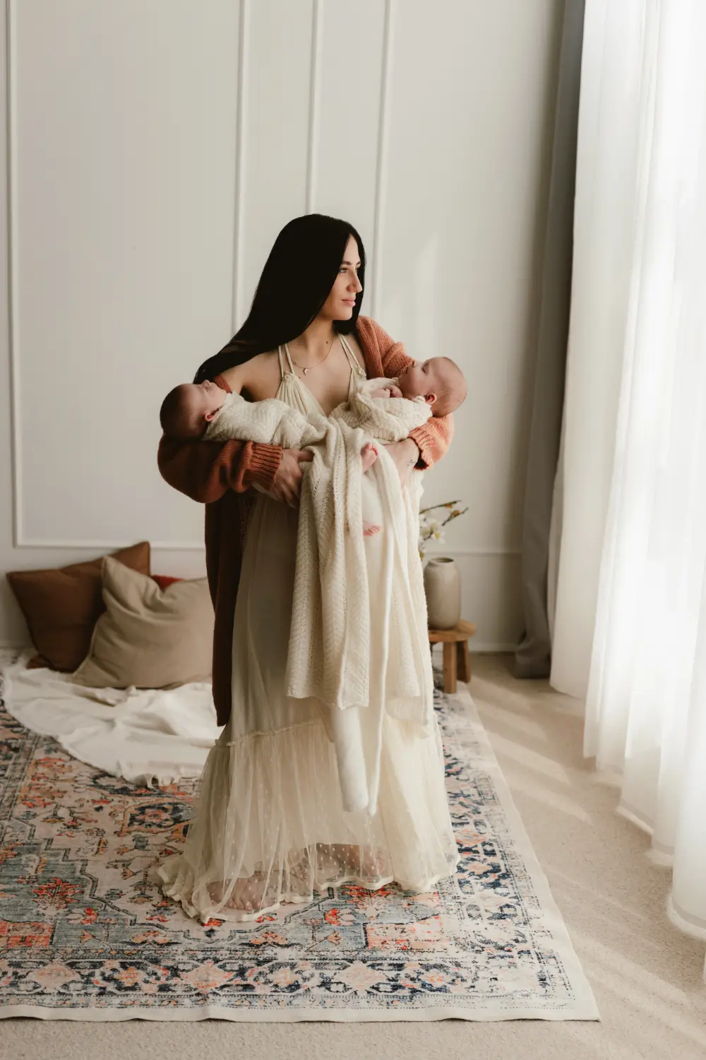 Newborn-fotenie-v-atelieri-Nitra7 Matka uspáva v náručí svoje novorodené bábätká počas novorodeneckého fotenia v ateliéri v Šuranoch.