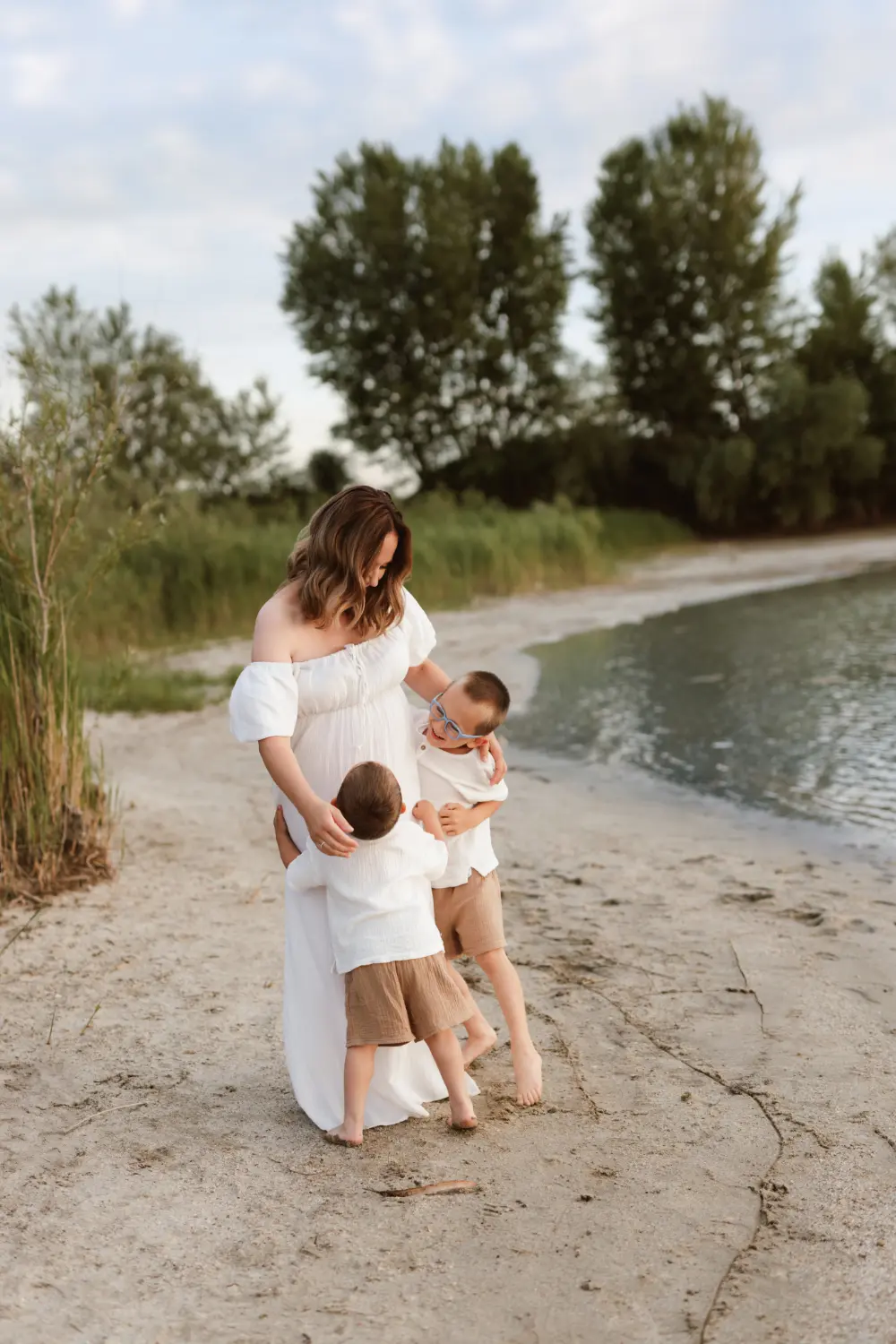  Mama bozkáva dieťa pričom ho drží v lone počas štýlového materského fotenia v ateliéri v Nitre 