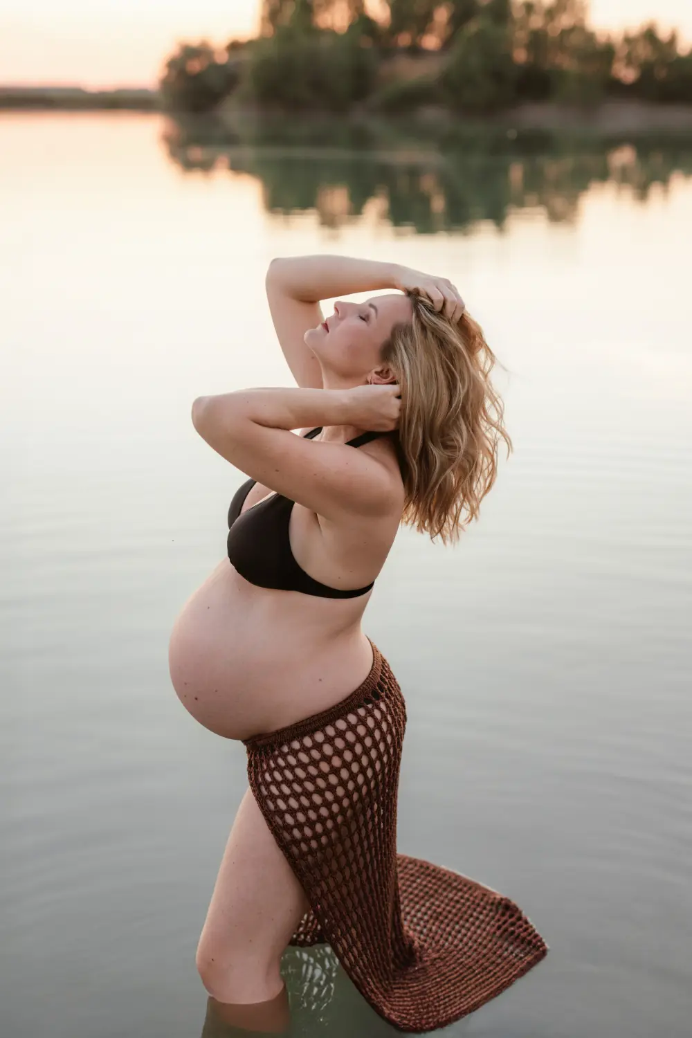 Tehotná žena jemne pózuje vo vode počas štýlového tehotenského fotenia pri jazere v Nitre a okolí 